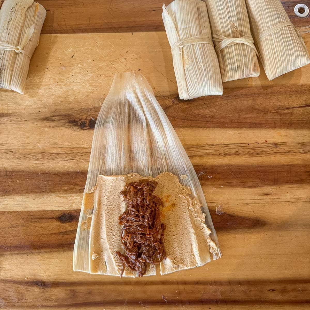 corn husk with masa and meat filling before wrapping