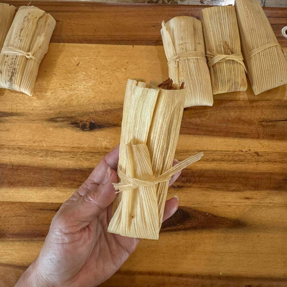 tamale being held up with more in the background