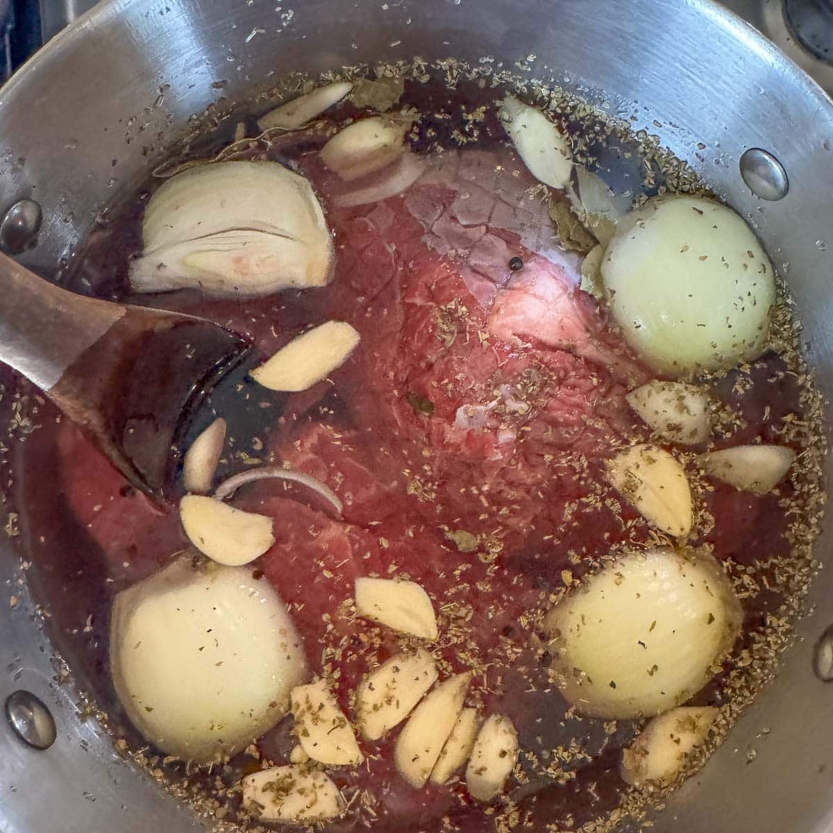 roasts cooking in a pot with water, onion, garlic, and spices