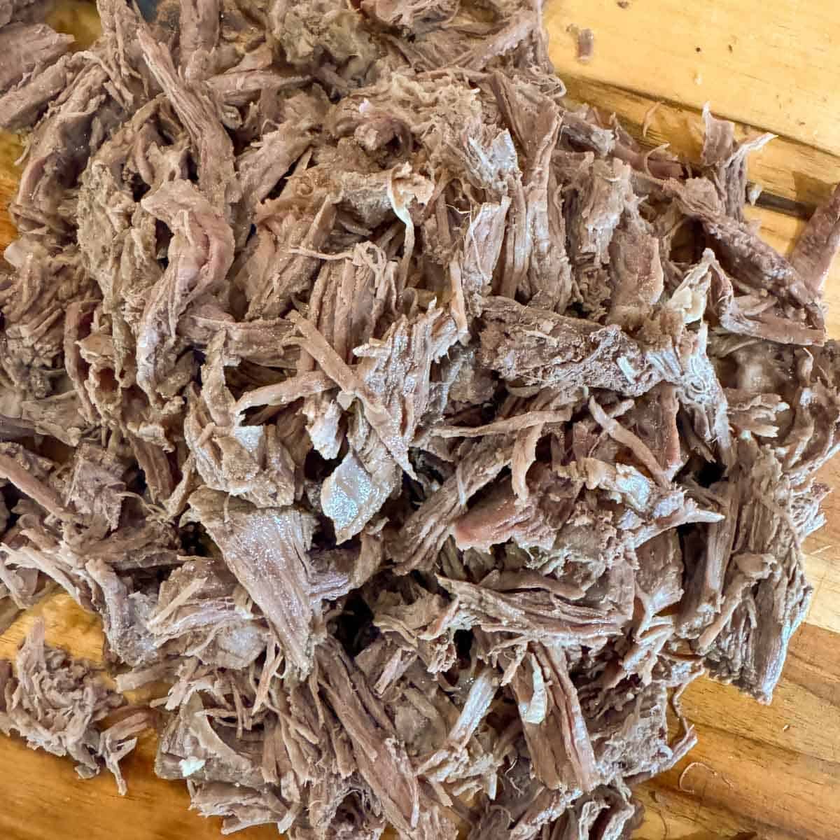 shredded beef on a cutting board