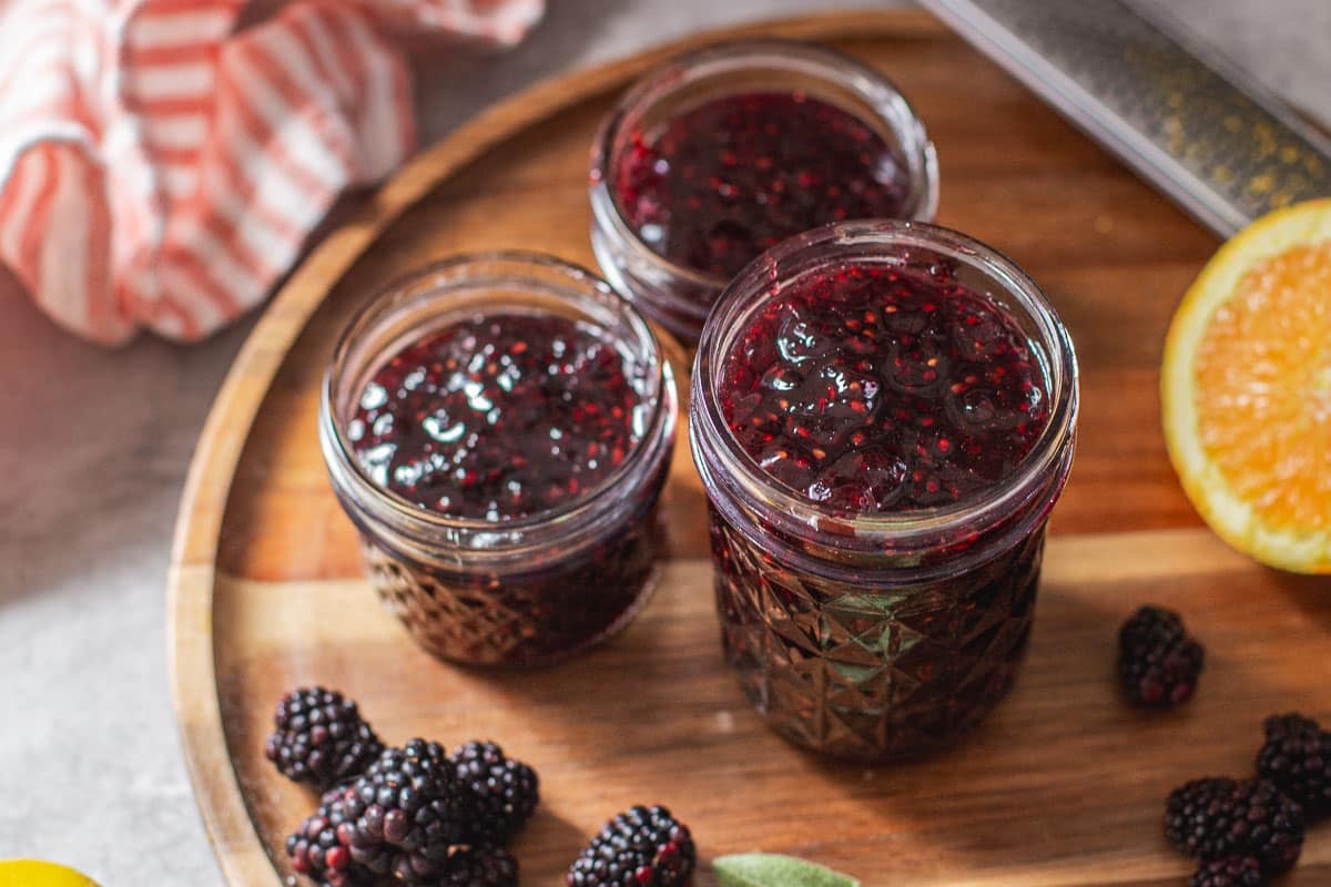 no pectin blackberry jam in jars beside fresh fruit.