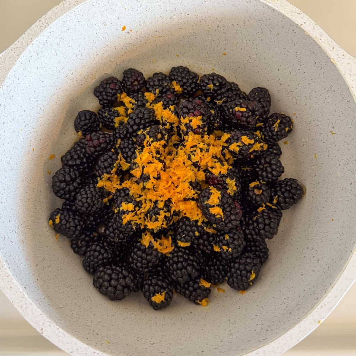 blackberries and orange zest in pot.