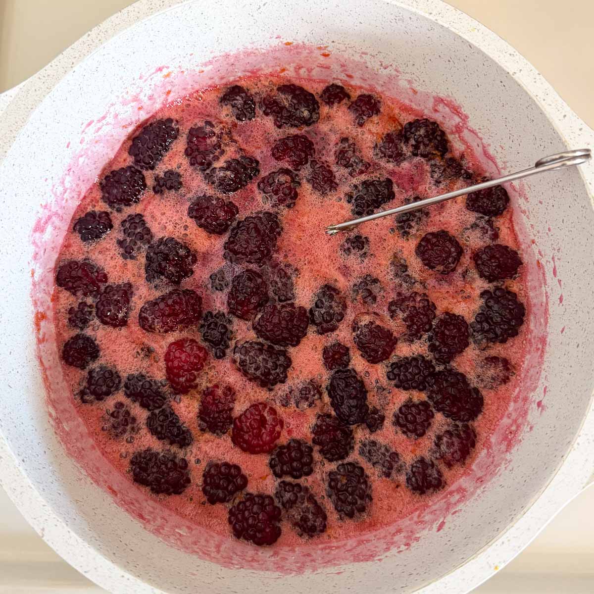 tea strainer with lemon seeds in boiling blackberry jam.