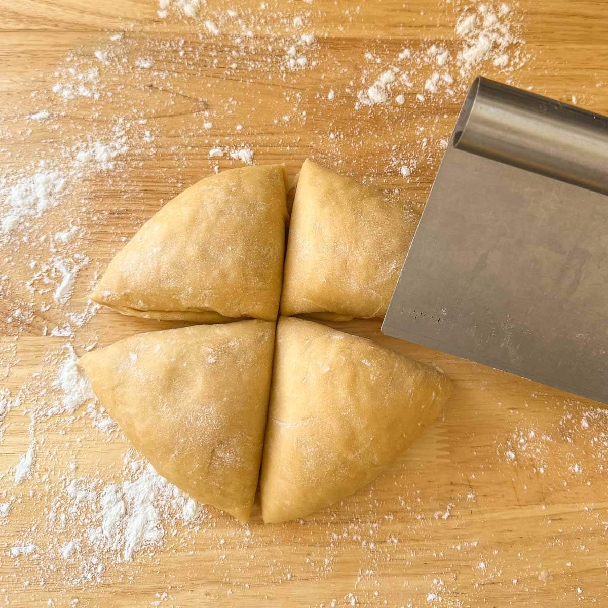 homemade egg noodle dough ball being cut into quarters.