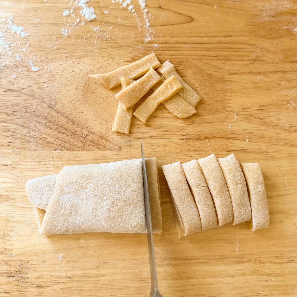 folded dough being cut into thick noodles.