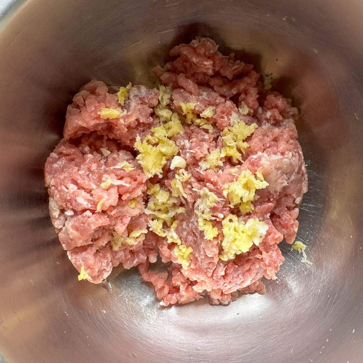 ground pork in a silver bowl with crushed garlic