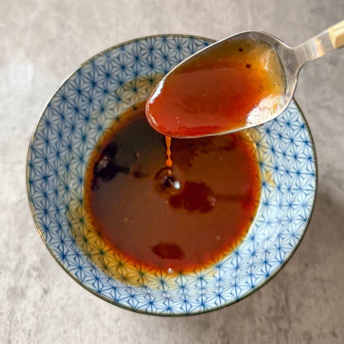 BBQ sauce mixture dripping from spoon into bowl.