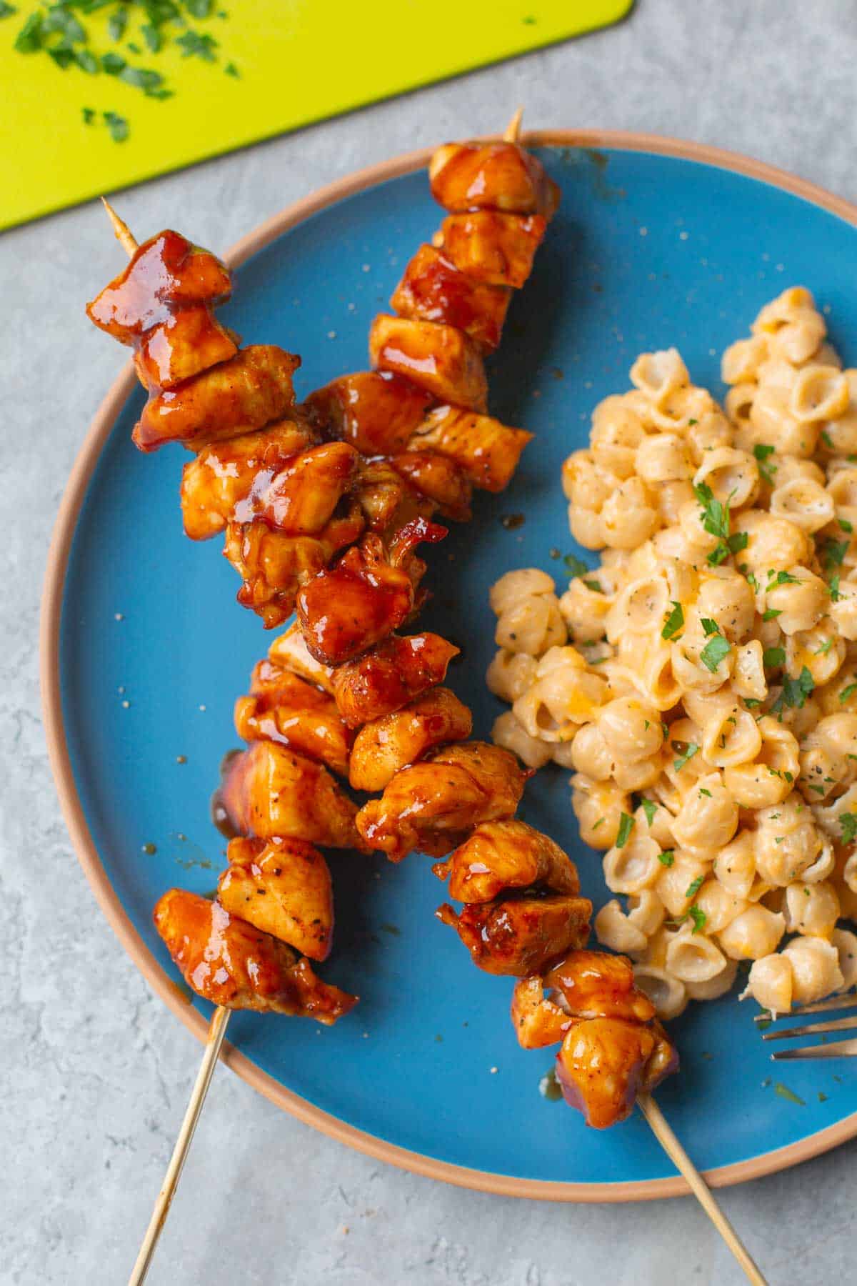 air fried bbq chicken on skewers beside mac and cheese.