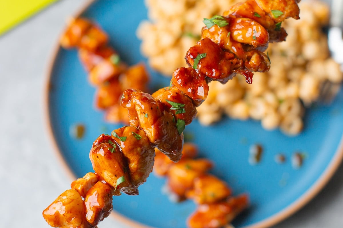 skewered air fryer bbq chicken above plate with mac and cheese.
