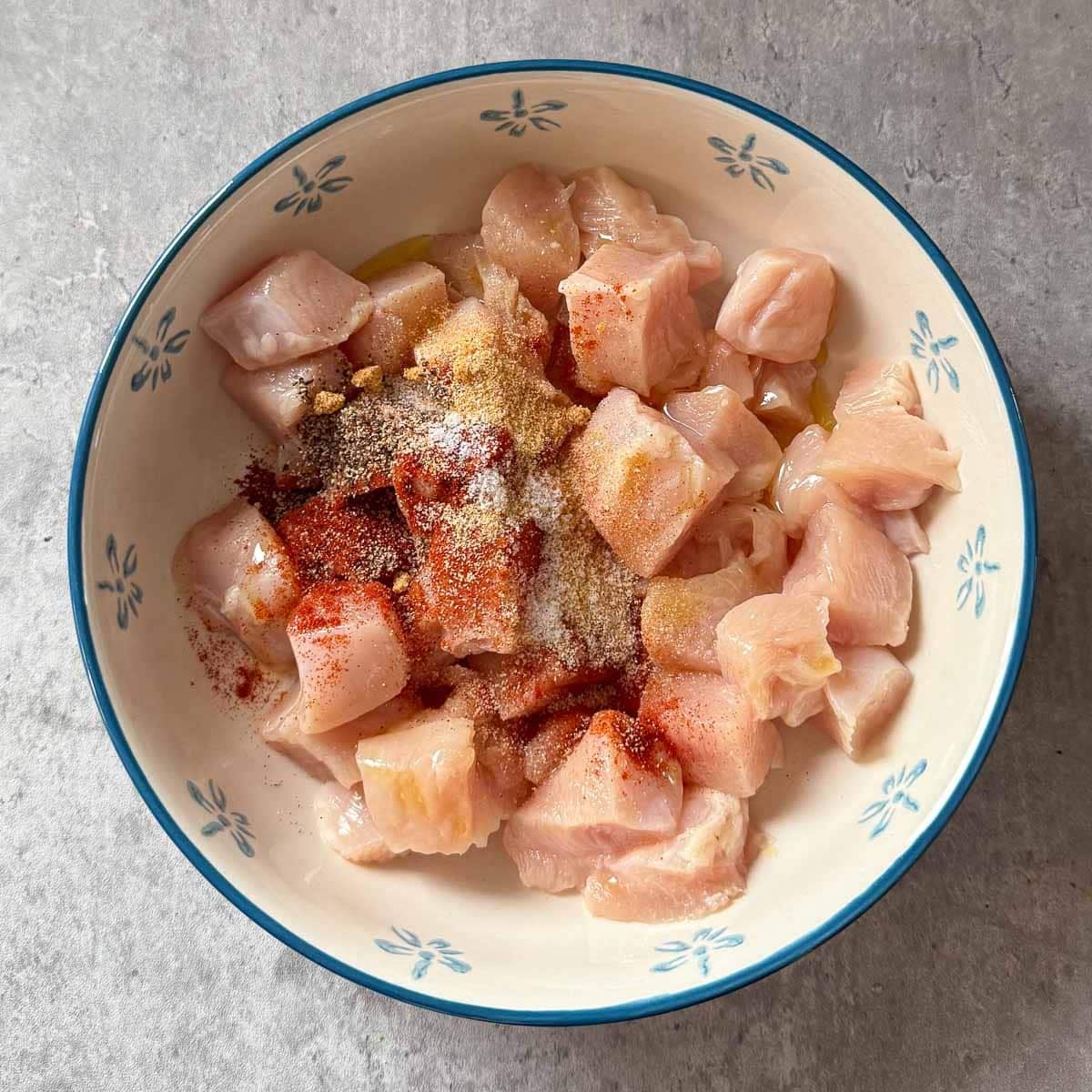 raw cubed chicken topped with spices.