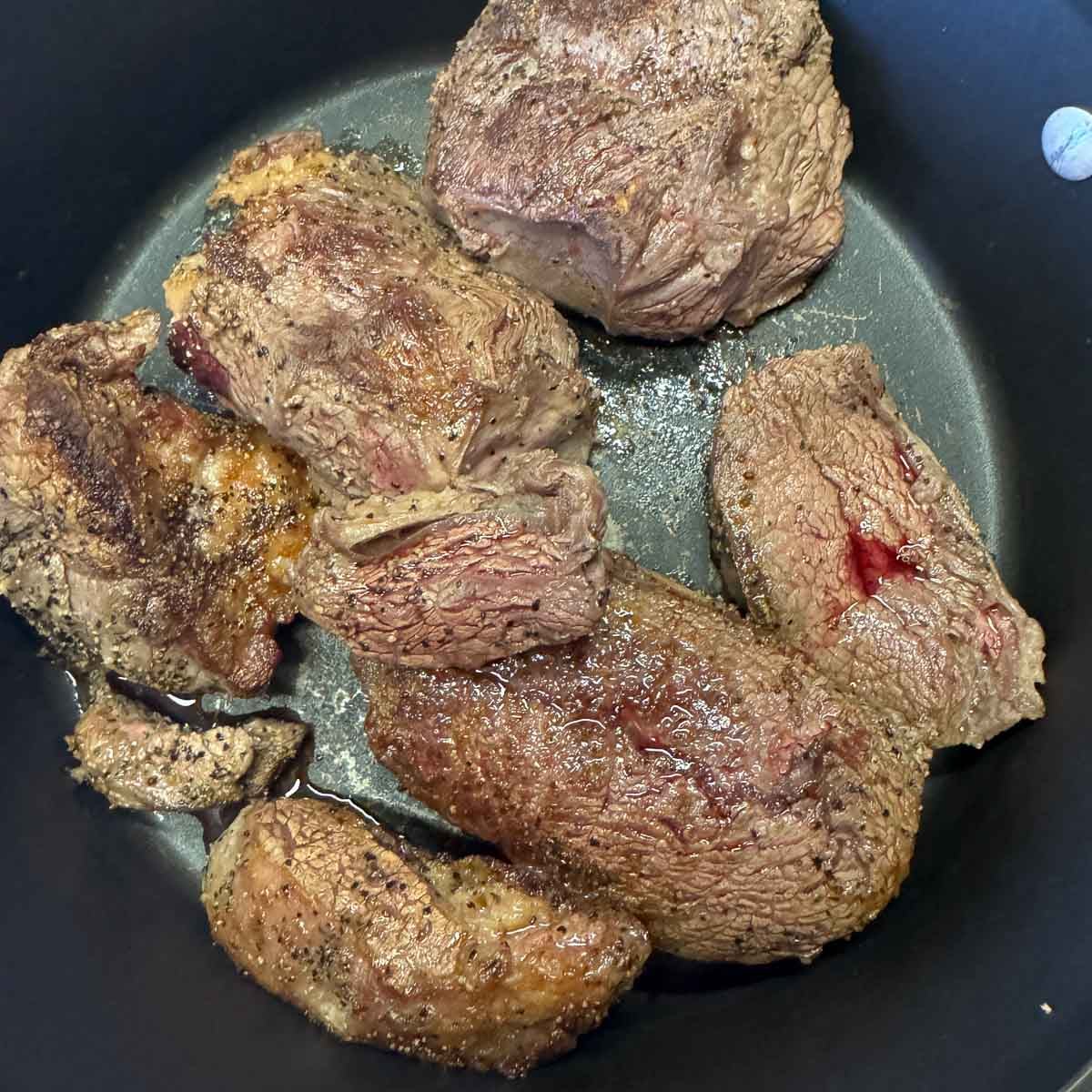 seared chuck roast chunks in a pan