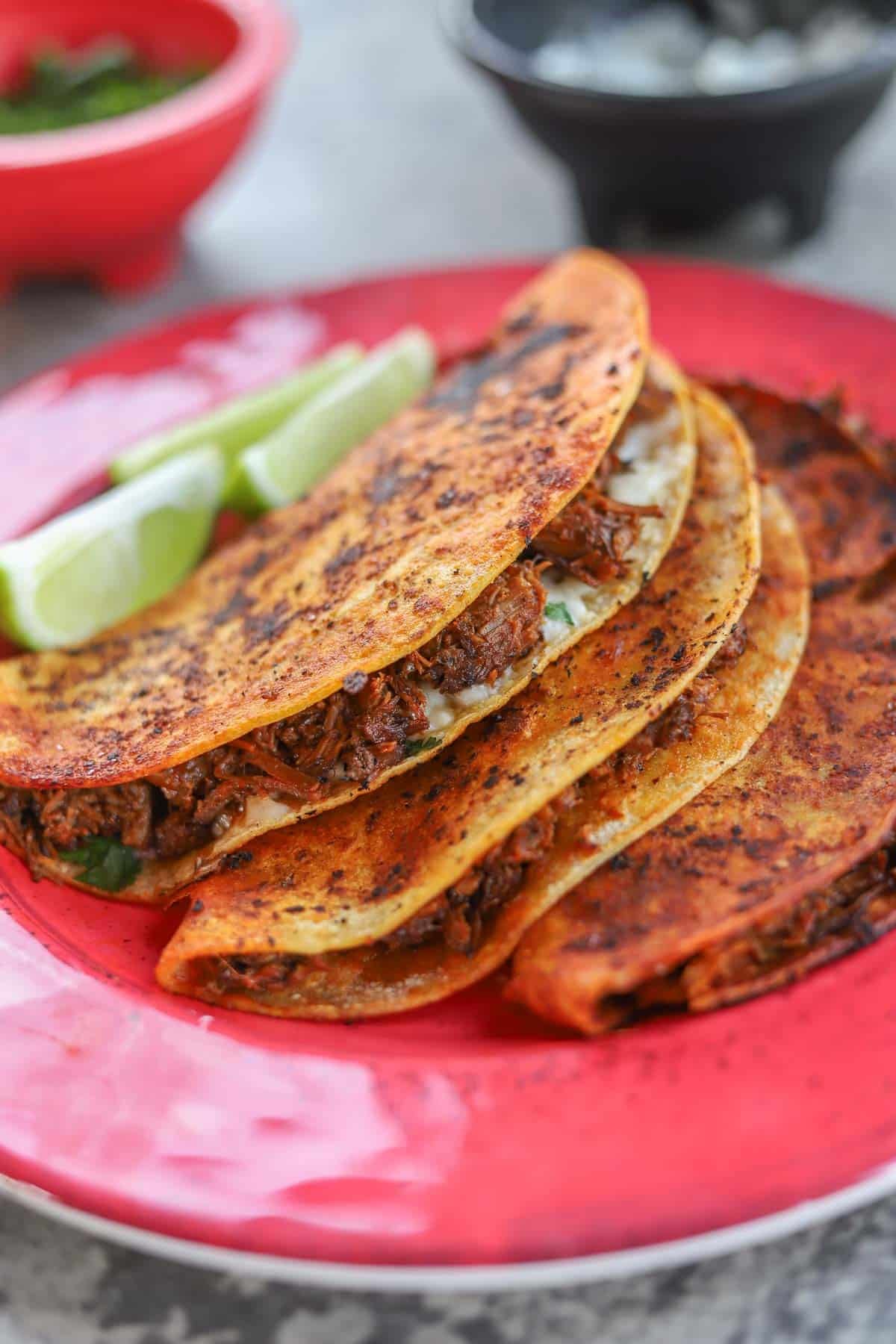 barria tacos stacked on each other with lime wedges.
