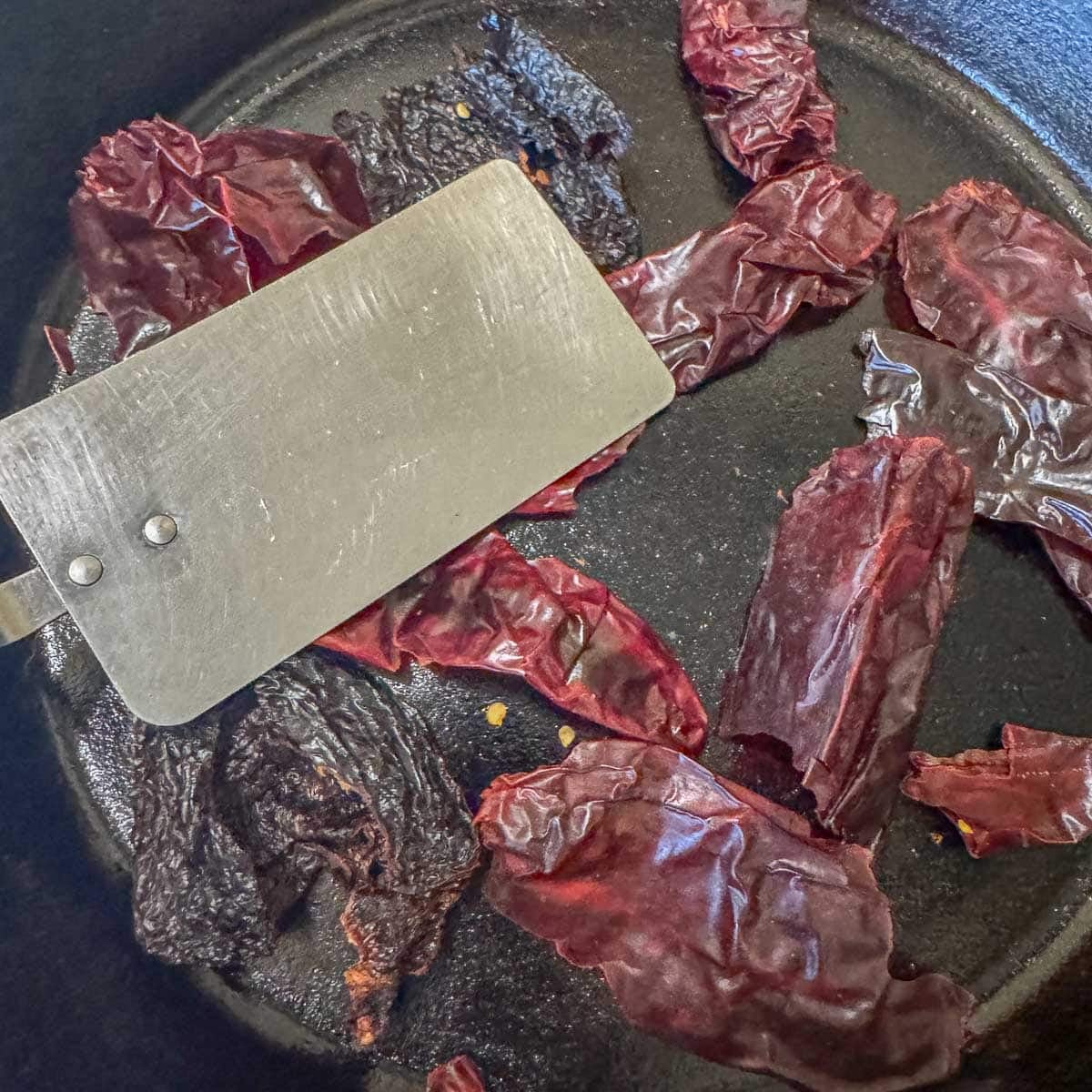 chiles in a cast iron skillet being toasted