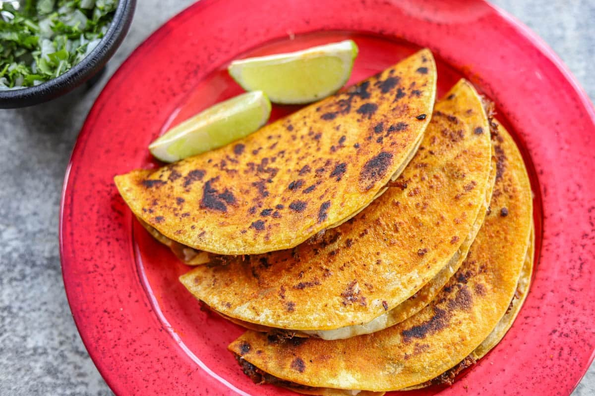 barria tacos with lime wedges on a red plate. 