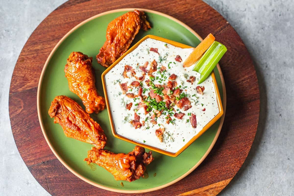 blue cheese dip for hot wings with buffalo wings and veggie sticks.
