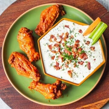 blue cheese dip for hot wings with buffalo wings and veggie sticks.