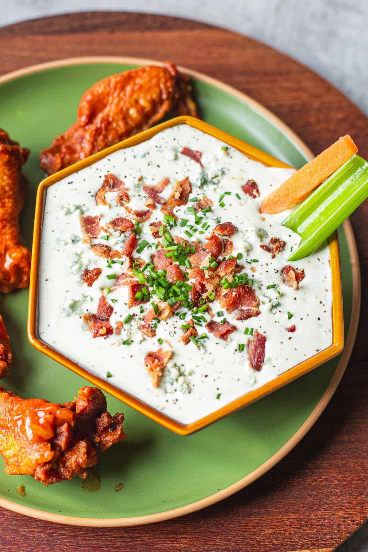 blue cheese dip for hot wings with buffalo wings and veggie sticks.