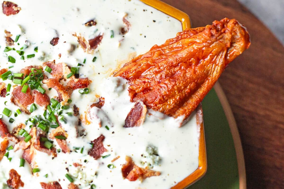 buffalo wing being dipped in blue cheese dip for hot wings.