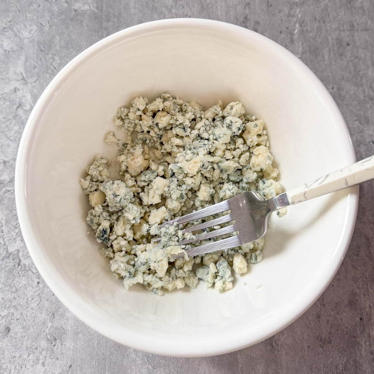 fork breaking down large blue cheese chunks.