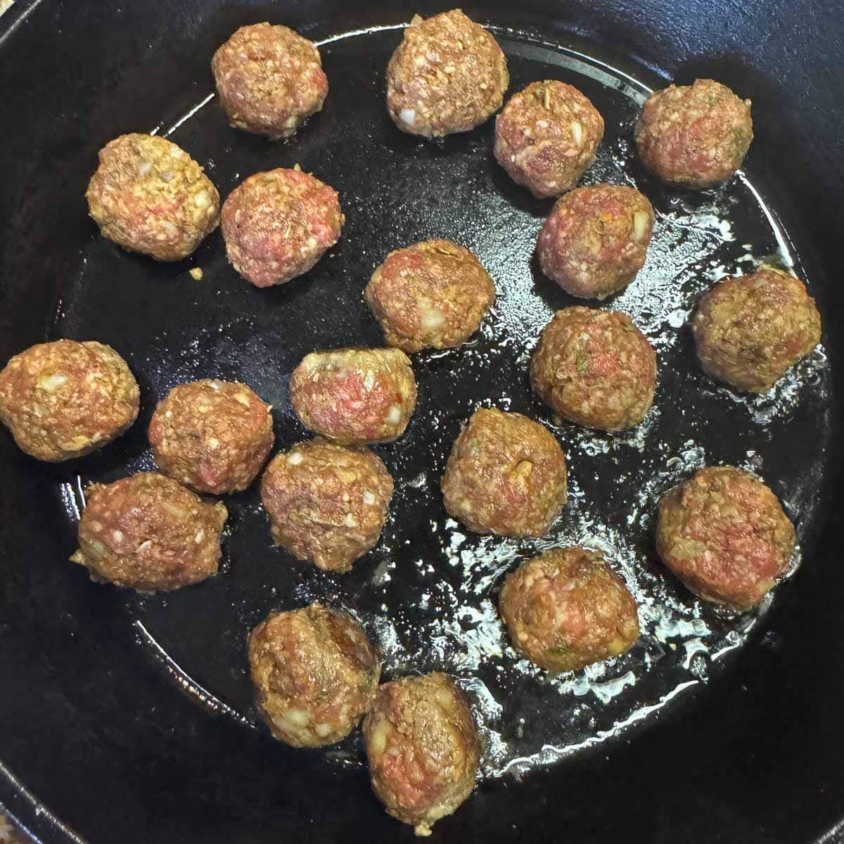 meatballs being cooked in a skillet