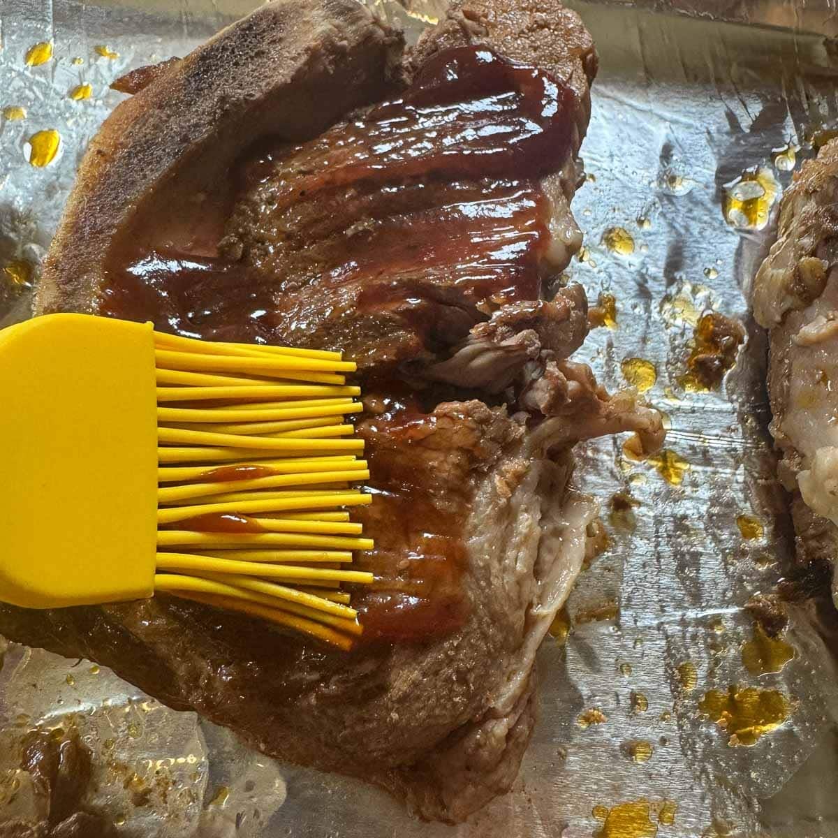 country style pork ribs being brushed with bbq sauce