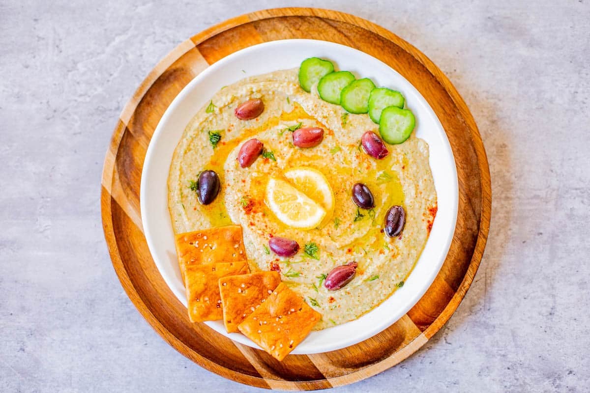 hummus without tahini topped with kalamata olives, lemon, cucumbers, pita chips.
