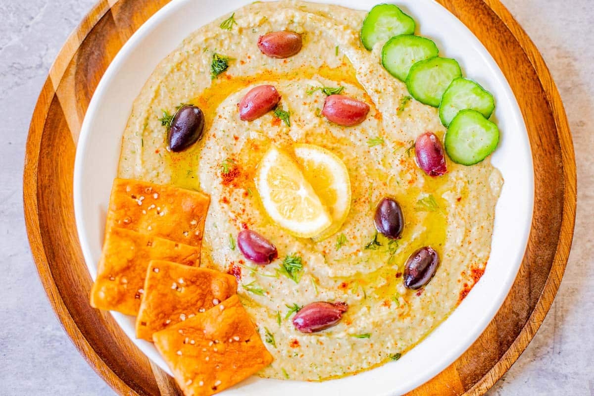 hummus without tahini topped with kalamata olives, lemon, cucumbers, pita chips.