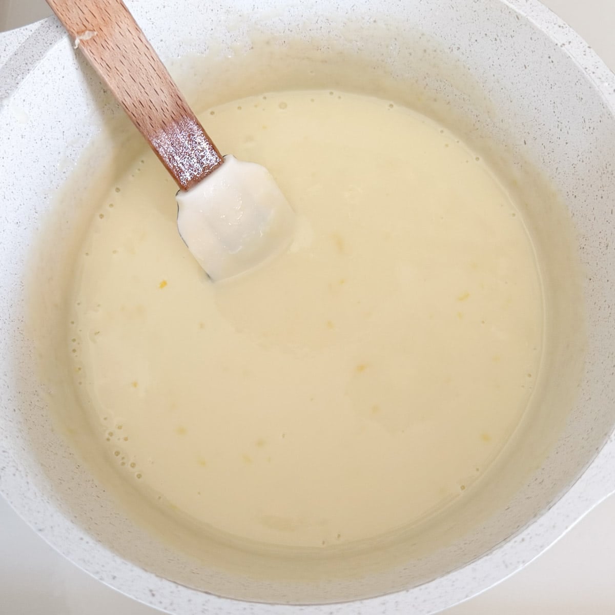 mixing lemon posset with spatula.