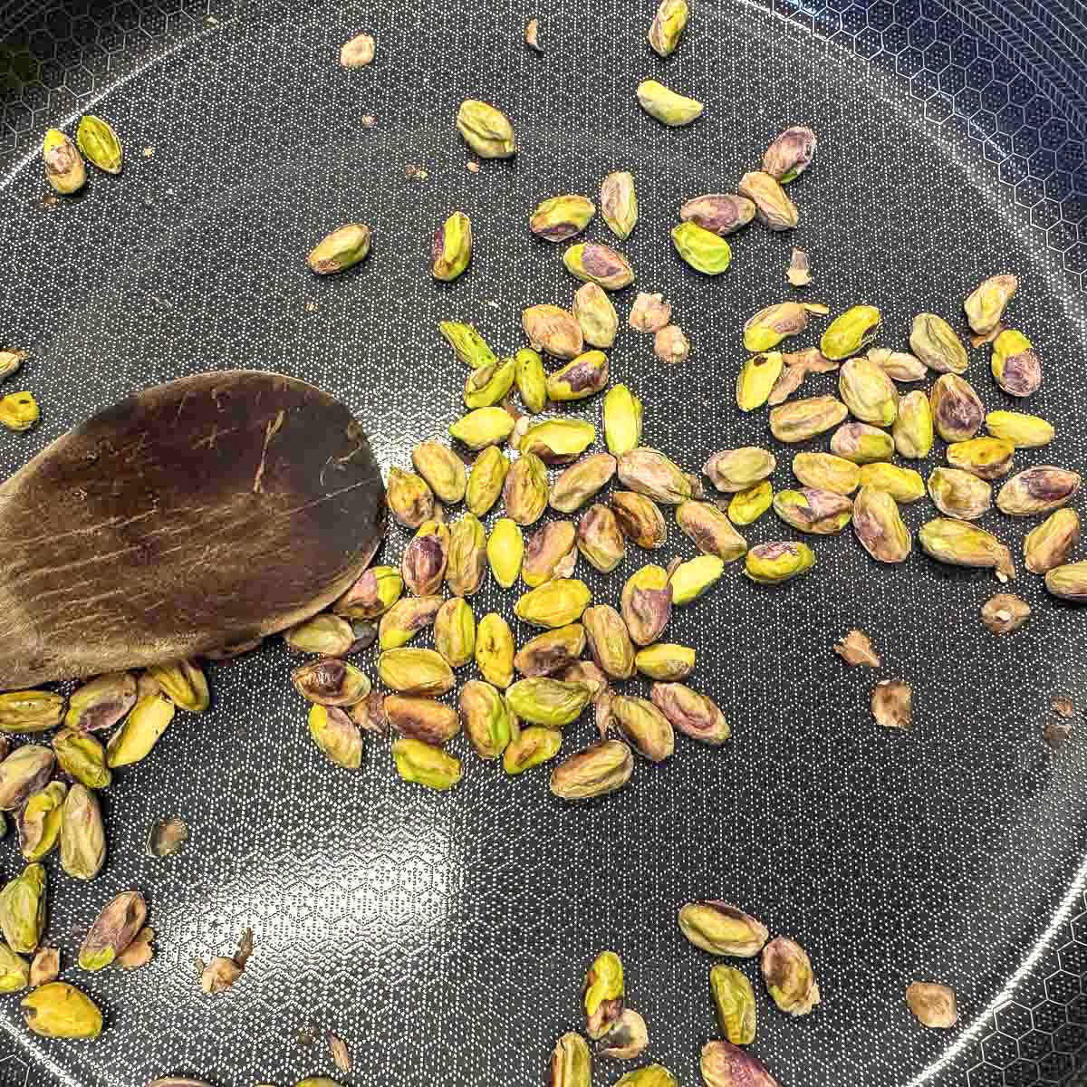stirring toasted pistachio in a pan