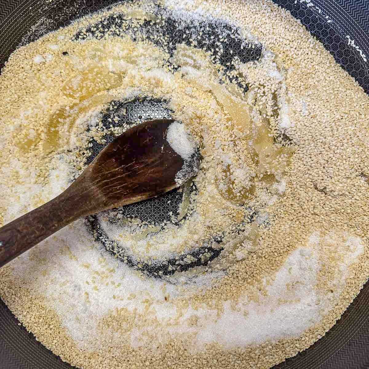 stirring sugar, honey, and sesame seeds in a pan