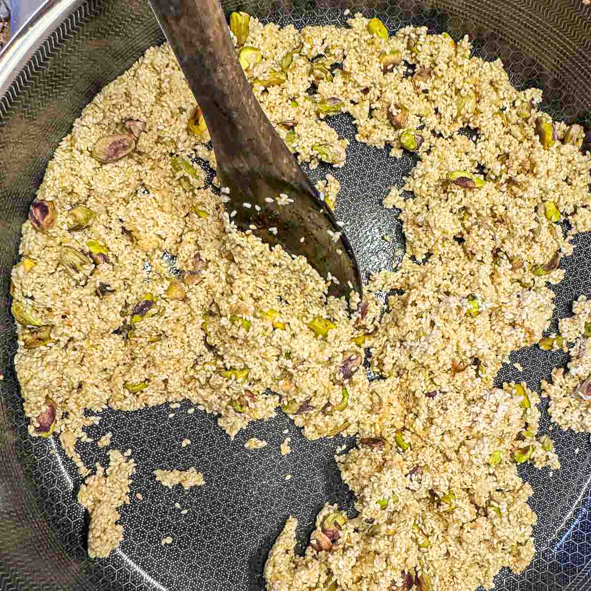 stirring sesame seed mixture in a pan with a wooden spoon