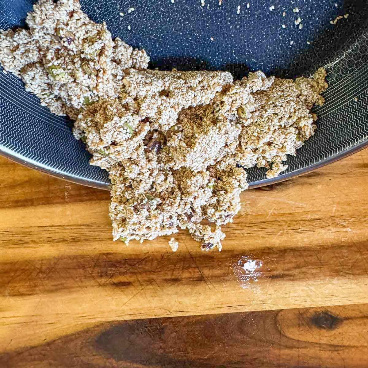 sesame and pistachio mix being poured out of pan onto cutting board