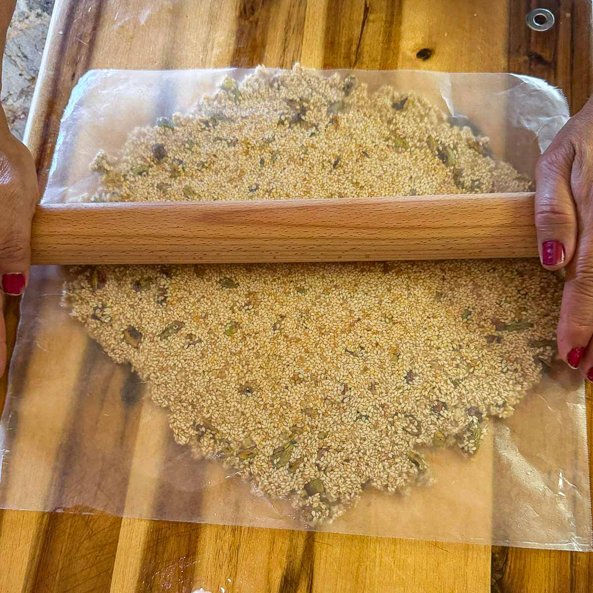 pasteli (simsim) being rolled flat with a rolling pin