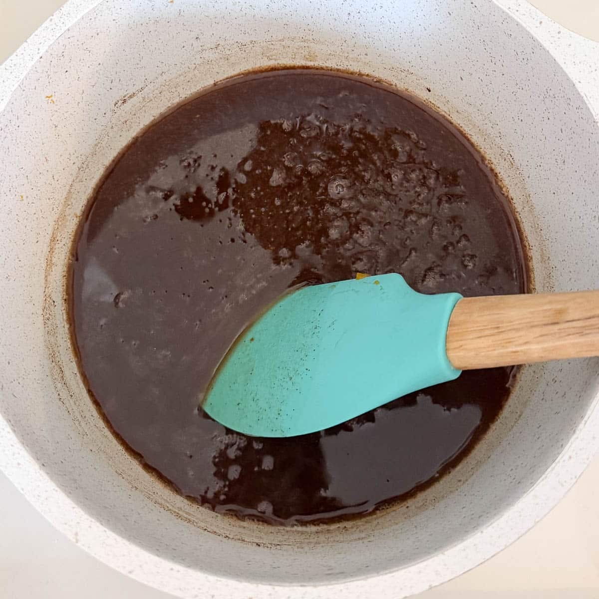 stirring pumpkin spice syrup with a blue spatula