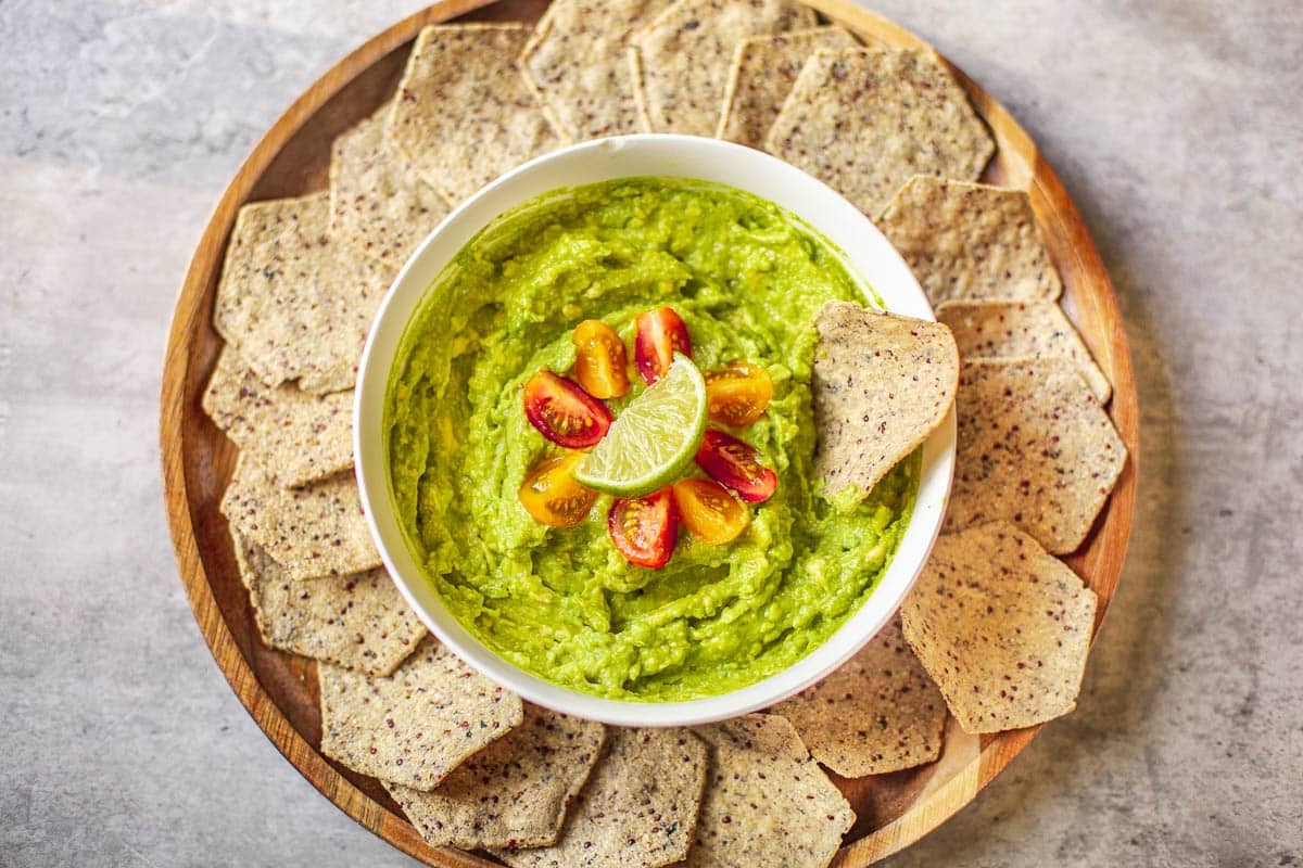4 ingredient guacamole garnished with cherry tomatoes and lime surrounded by tortilla chips.
