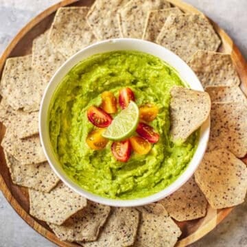 4 ingredient guacamole garnished with cherry tomatoes and lime surrounded by tortilla chips.