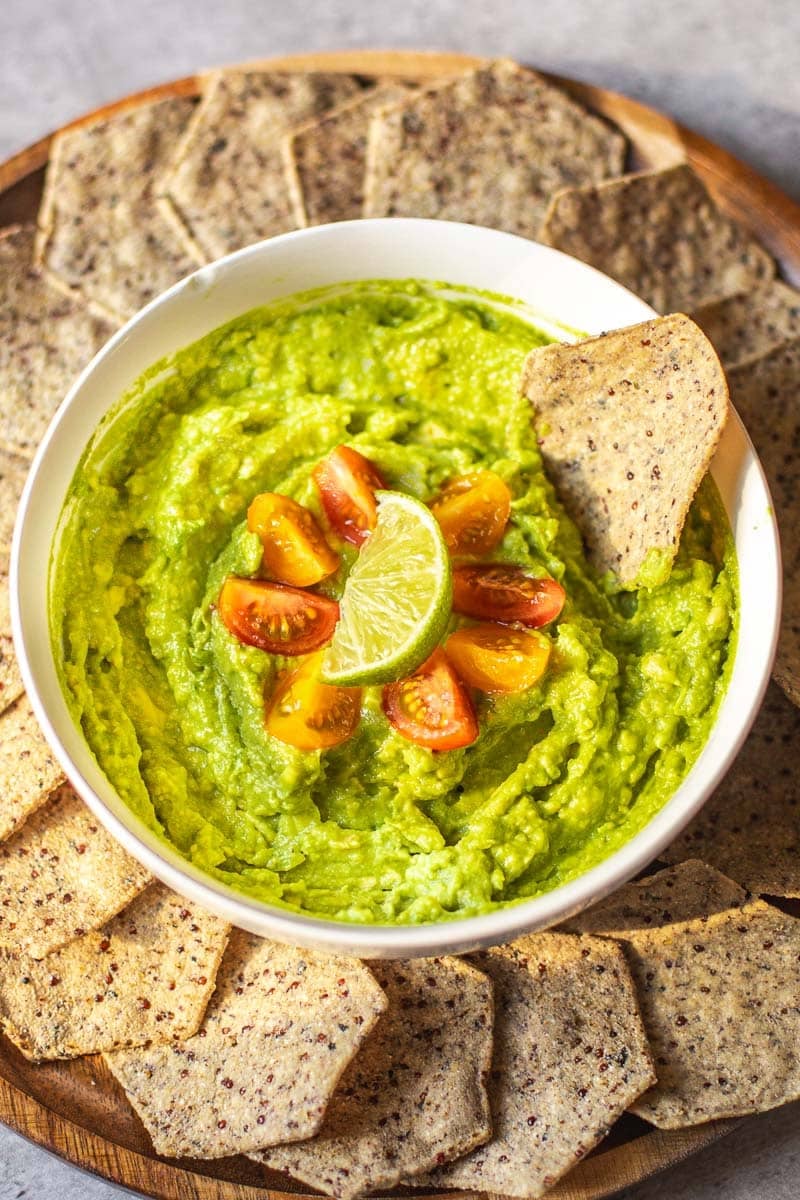 4 ingredient guacamole garnished with cherry tomatoes and lime surrounded by tortilla chips.