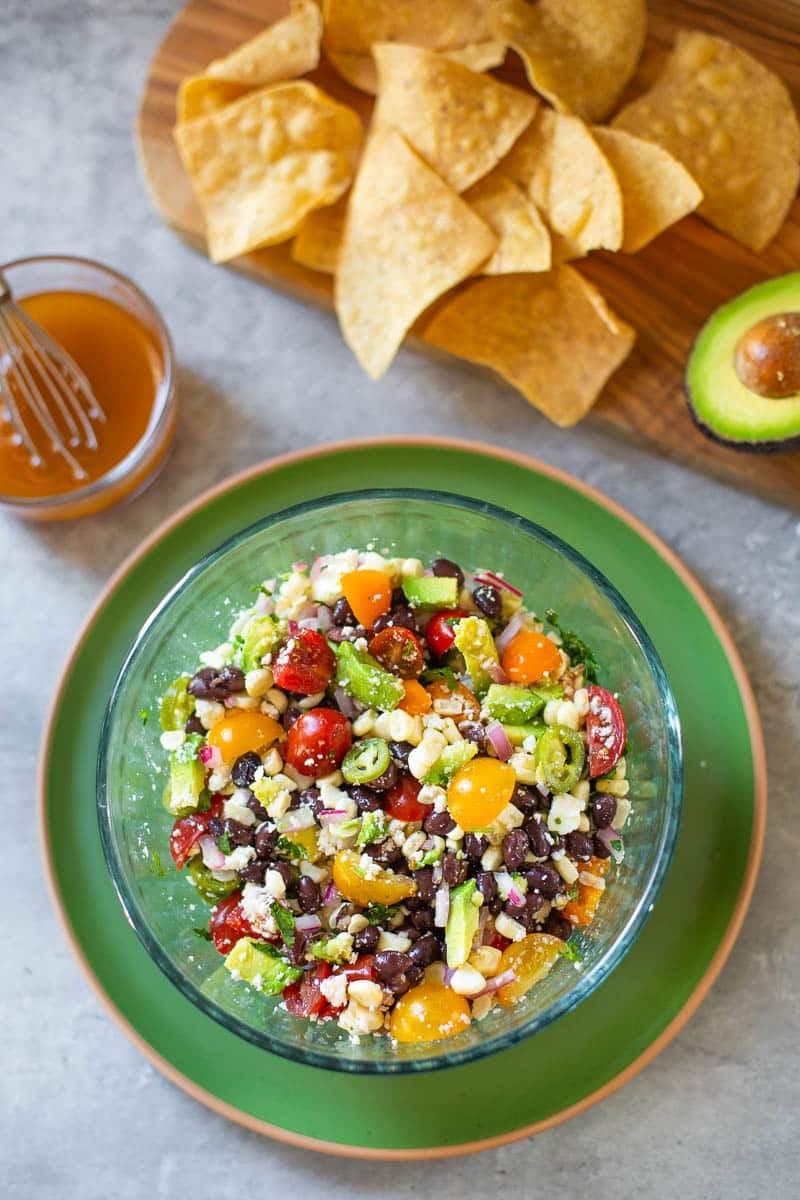 black bean and corn salsa beside vinaigrette, chips, avocado.