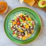 black bean and corn salsa beside vinaigrette, chips, avocado.