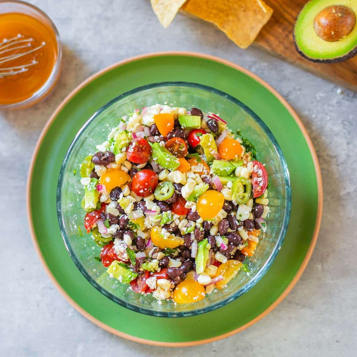 black bean and corn salsa beside vinaigrette, chips, avocado.