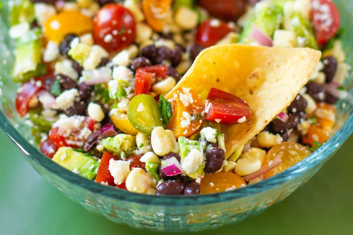 black bean corn salsa being scooped with a tortilla chip.