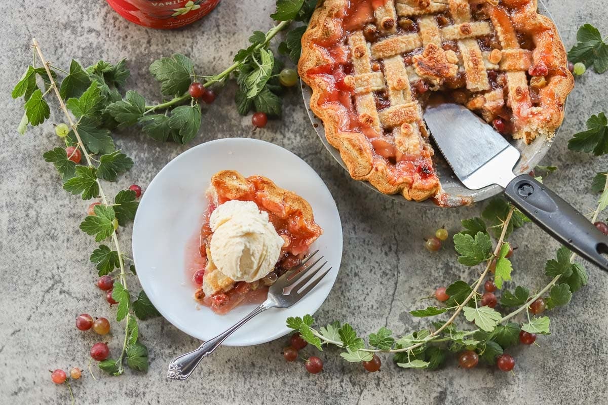 gooseberry pie with a slice cut out of it and a slice of pie on a white plate