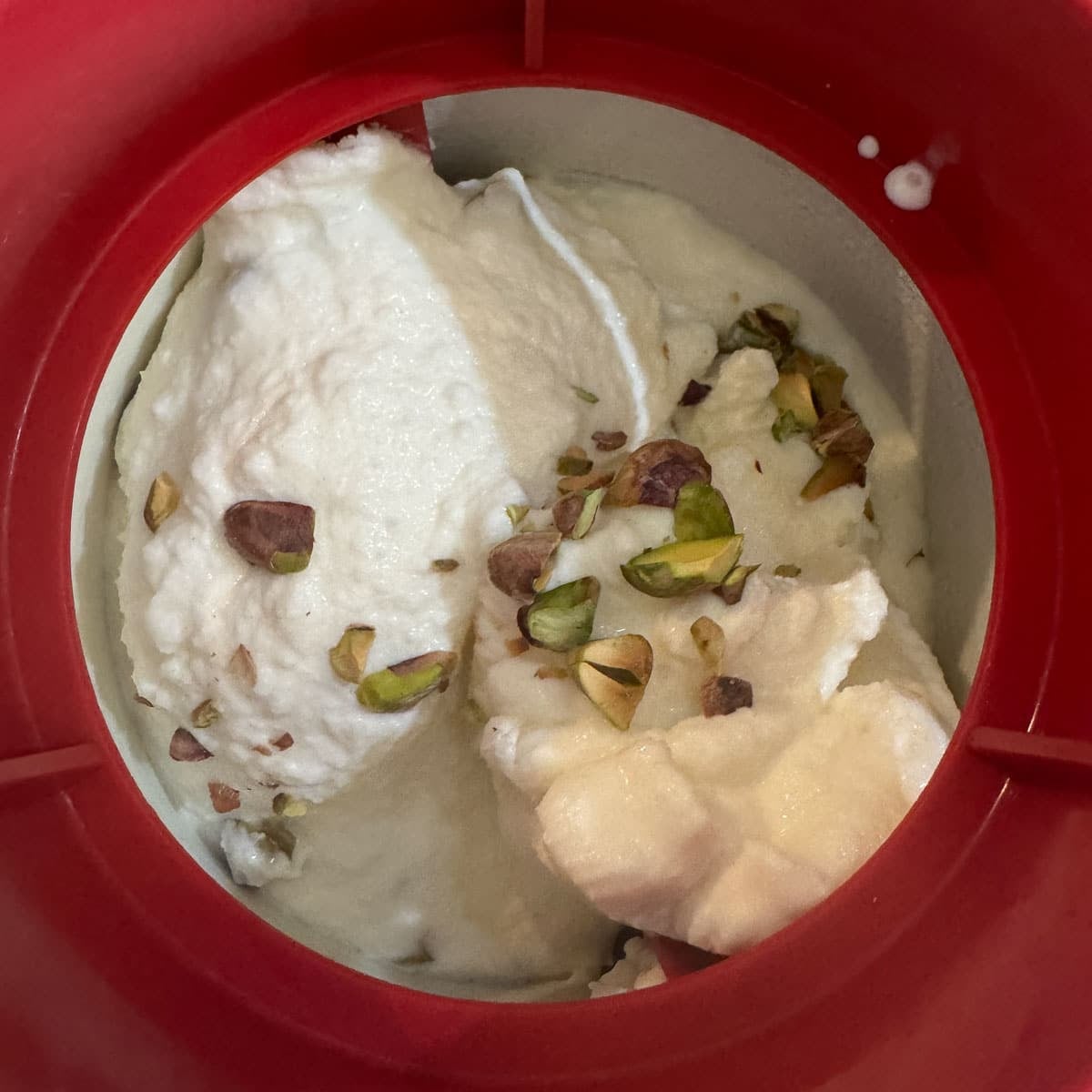 vanilla ice cream and pistachios in a red ice cream maker