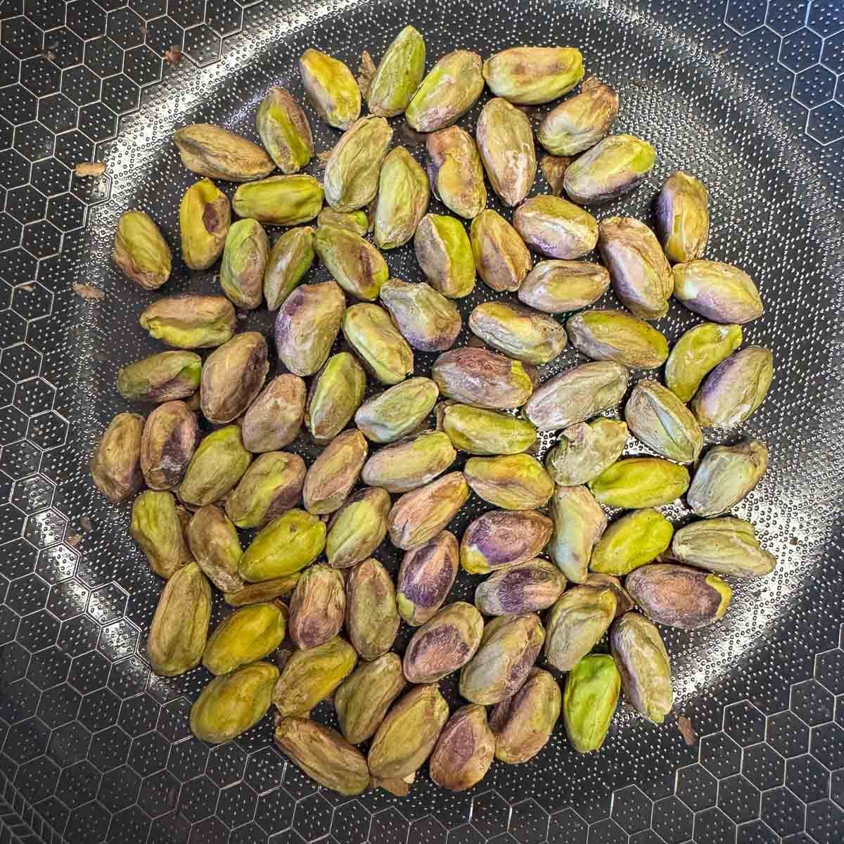 pistachios in a pan being toasted