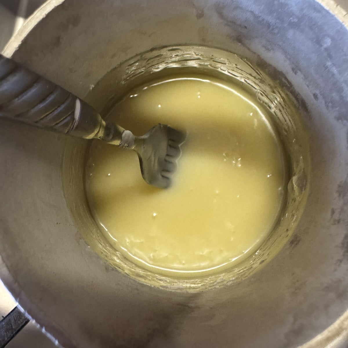 white ganache in a pot being stirred by fork