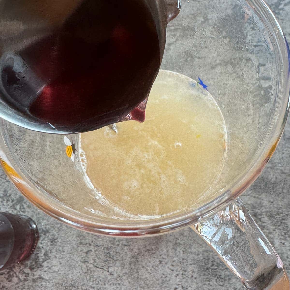 pouring lavender syrup over lemon juice and water in a pitcher