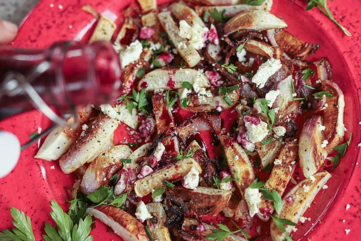 roasted turnips being drizzled with pomegranate syrup