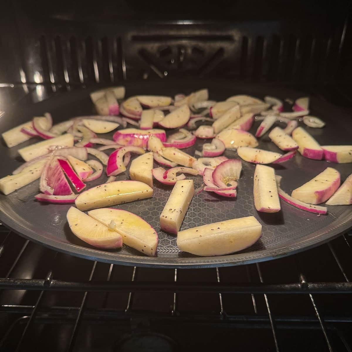 turnips and onions on a pan in the oven