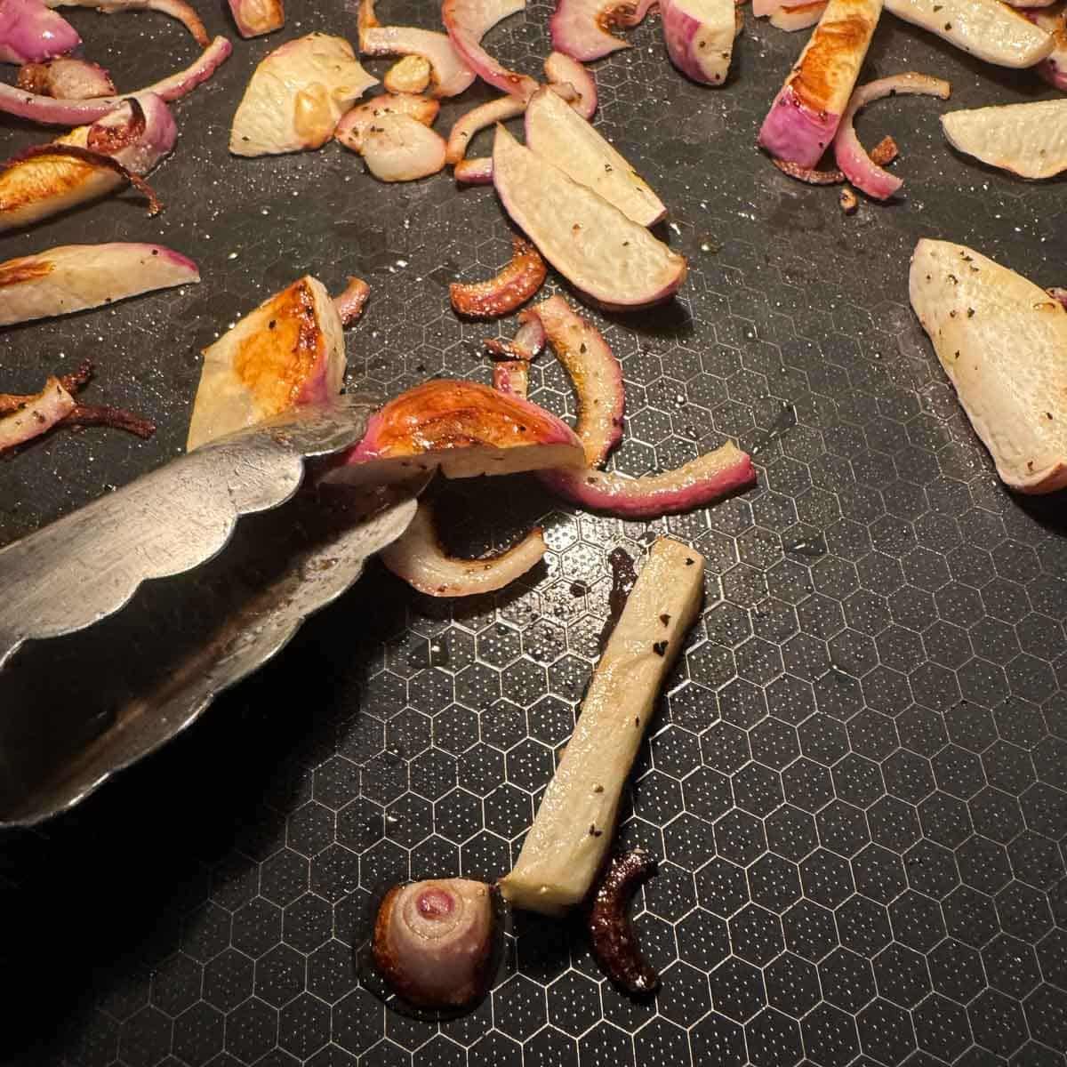 flipping roasted turnips on a pan