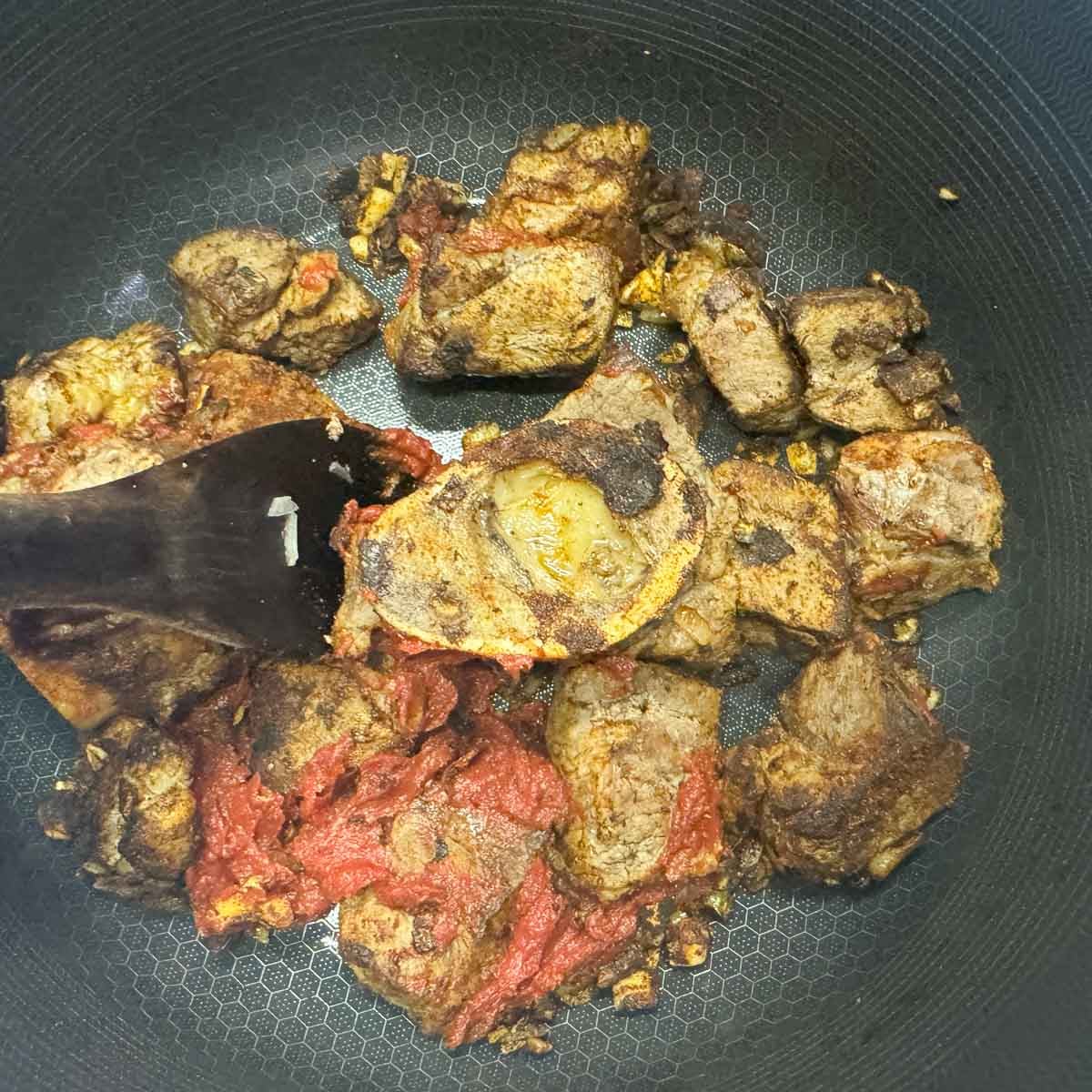 meat, onions, and tomato paste in a pot